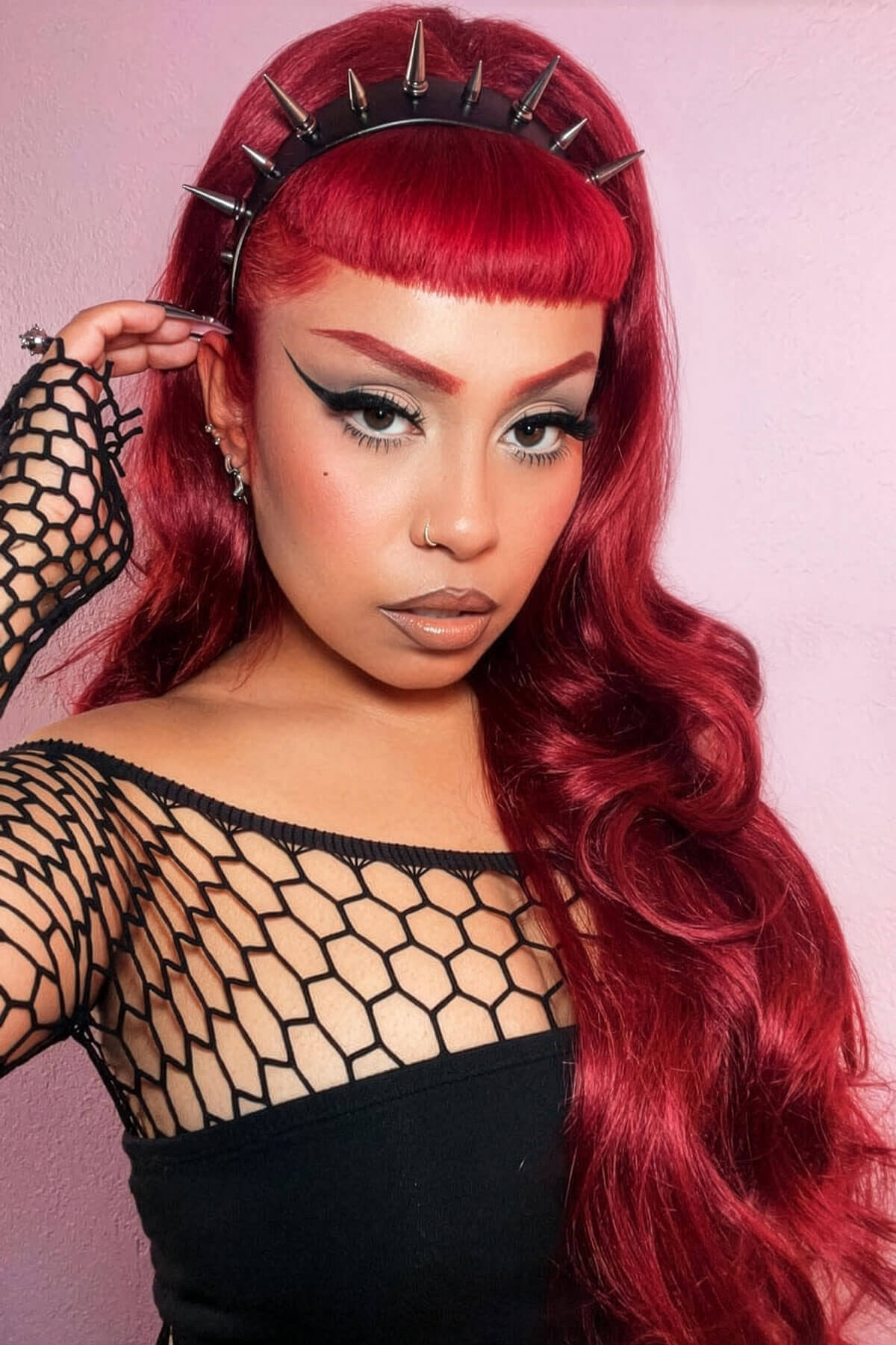 Woman with vibrant red hair and a spiked headband against a pink background. High crown long, wavy half wig and volume ring, cherry red: Bardot 39