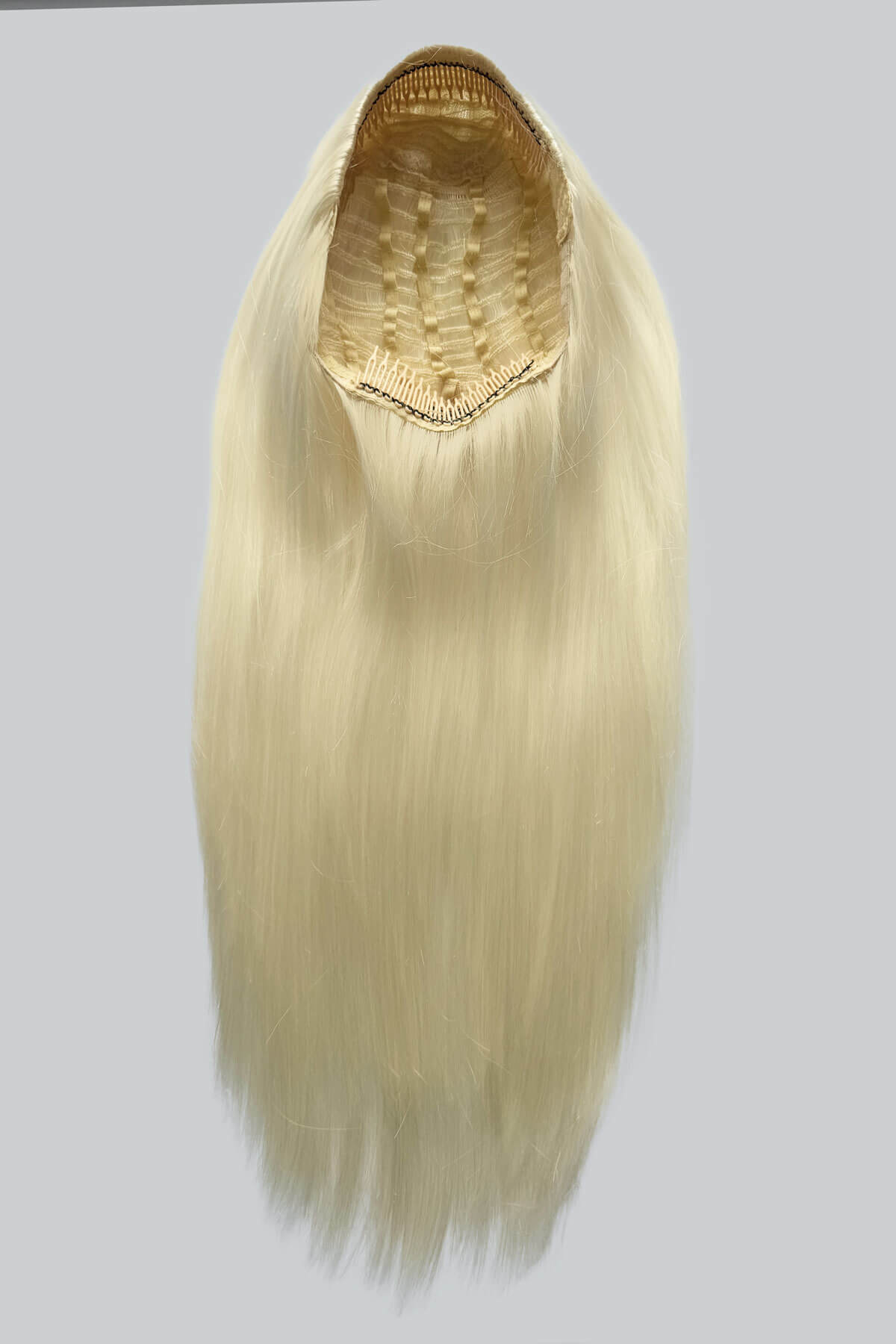 Blonde hair extension on a gray background. Straight platinum blonde half wig hairpiece (3/4 wig): Shannon platinum 1001