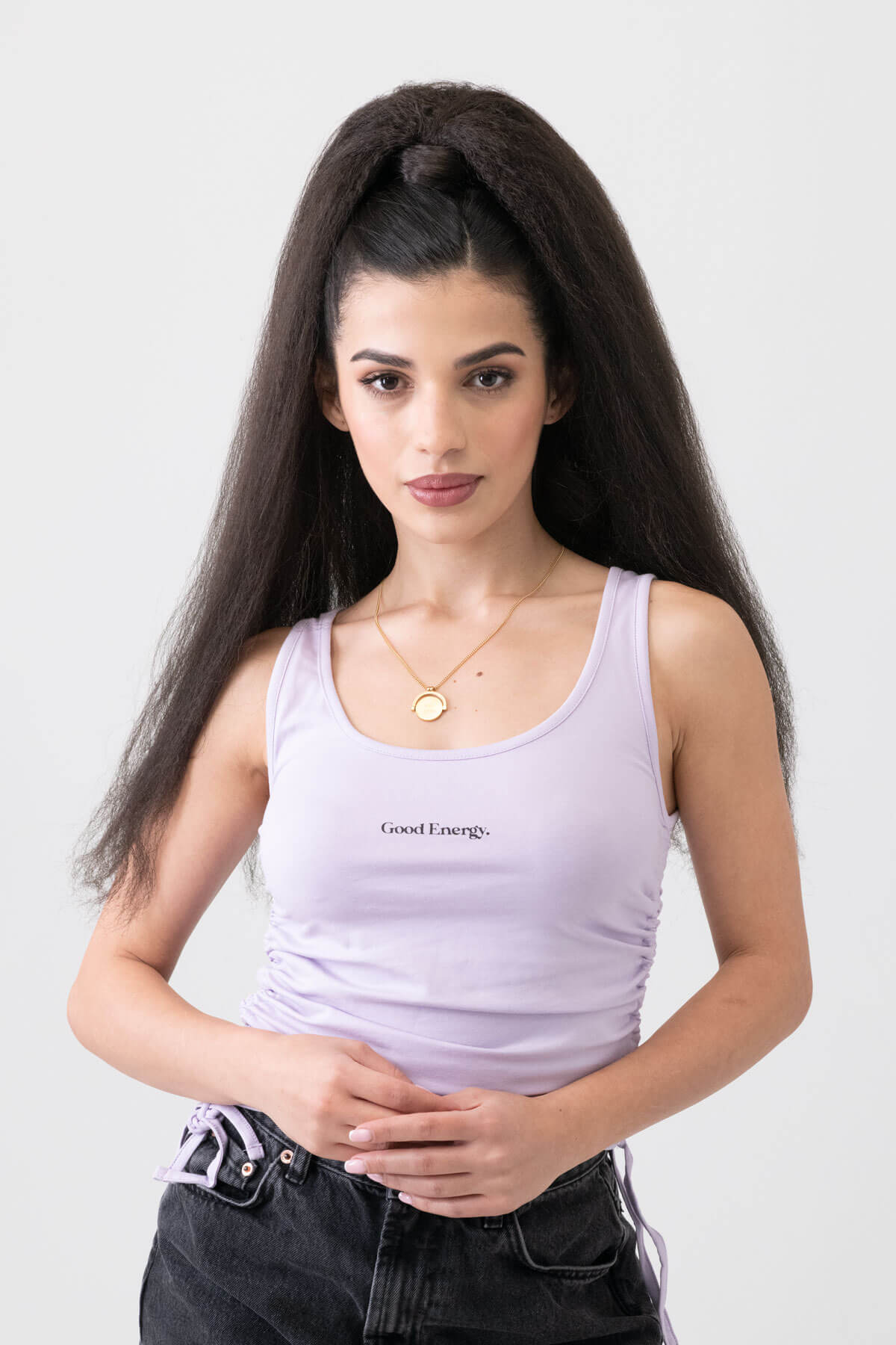 Woman wearing a light purple tank top with 'Good Energy' text on a plain background. Long Yaki perm ponytail extension with tight kinks and waves: Indi dark brown 4
