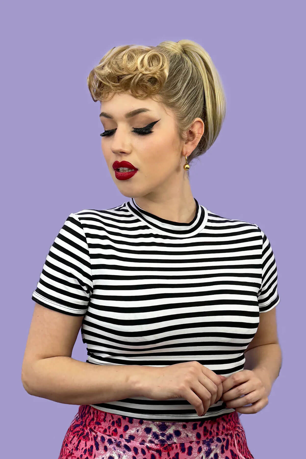 Woman wearing a black and white striped shirt against a purple background. Curly 1940s style clip-in fringe hairpiece/clip-in bangs: Bunny black 1B