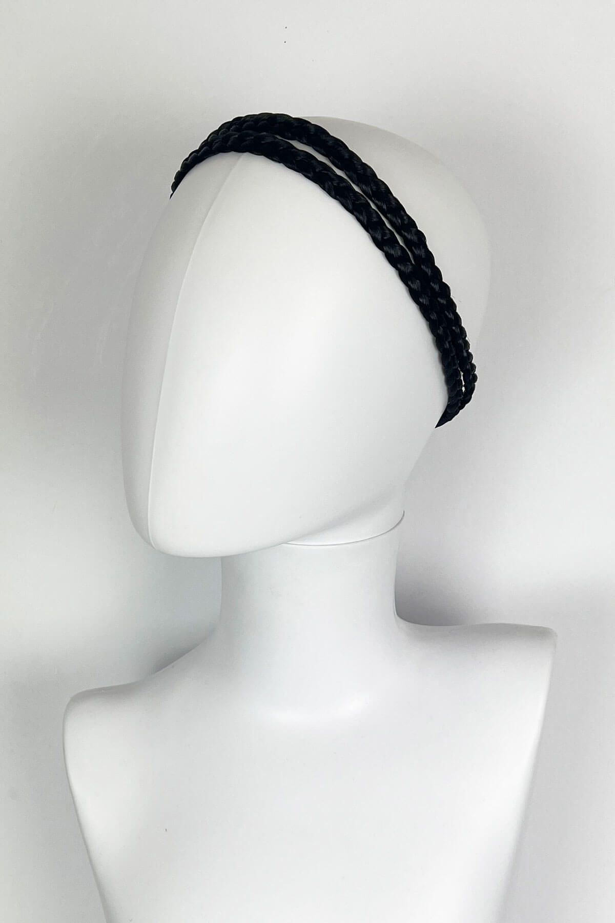 Black braided headband on a mannequin head against a white background. Plaited double hairband: Mira : black 1b