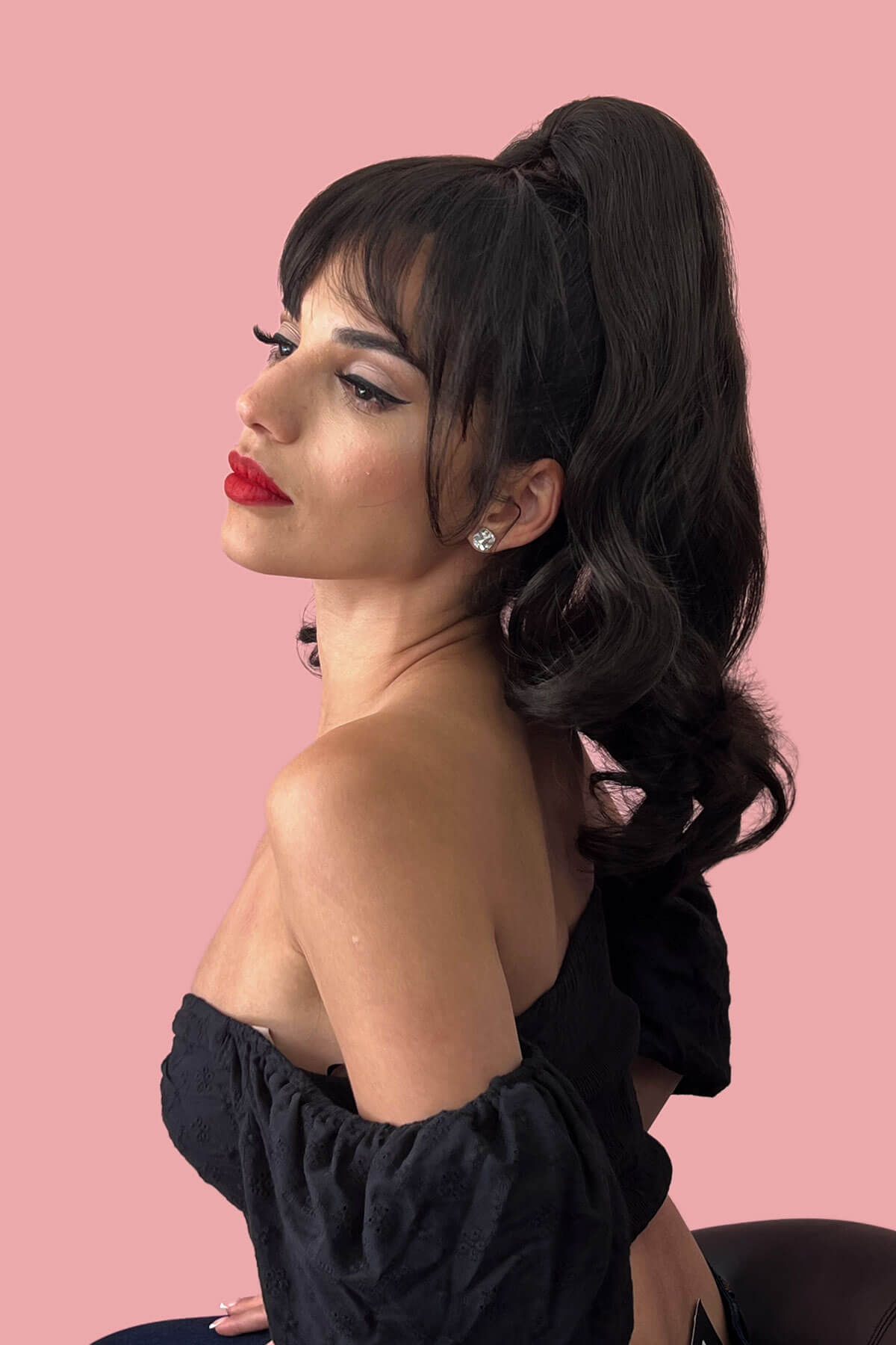 Woman with styled hair and red lipstick against a pink background. Clip in fringe hairpiece/clip-in bangs, gently feathered with face framing whisps: Delia black 1B