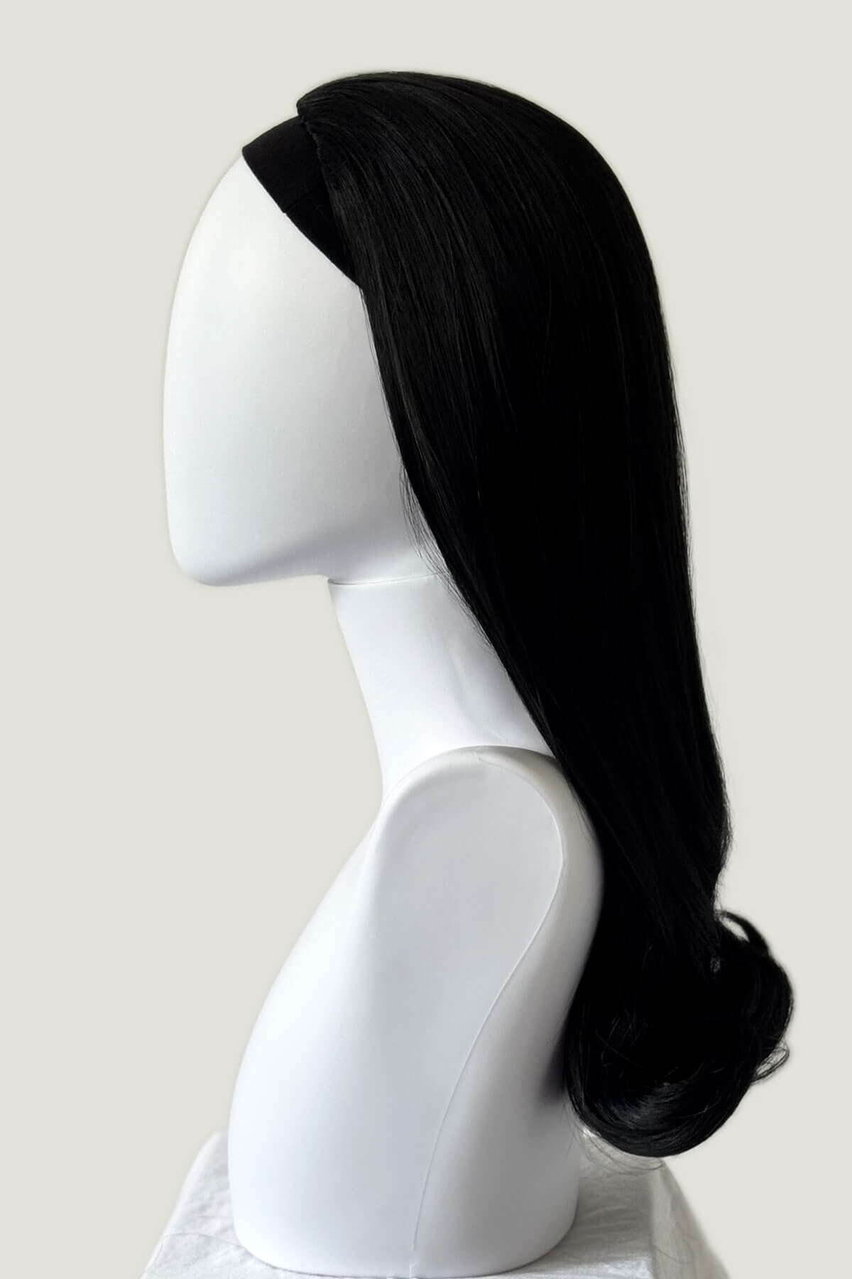 Black hair extension on a mannequin head against a white background. 1960s Retro high crown, half wig hairpiece, long with hair flip: Priscilla black 1b