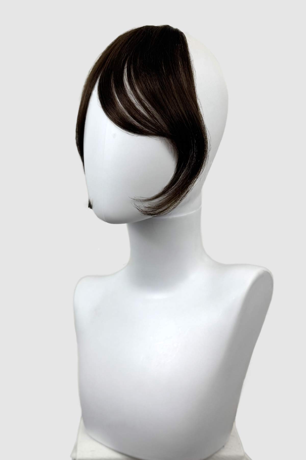 Brown hair clip-in extension on a white mannequin head against a white background. Clip in fringe hairpiece/clip-in curtain bangs, with long, face framing wisps: Sabrina chestnut brown 8
