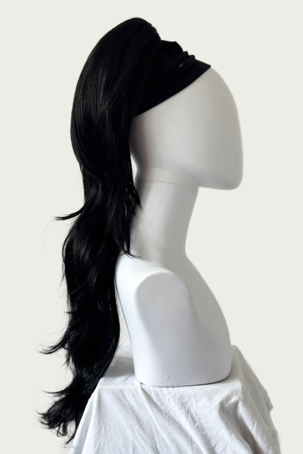 Black hair wrap on a mannequin head against a white background. Clip-in ponytail hairpiece extension: Olivia black 1B