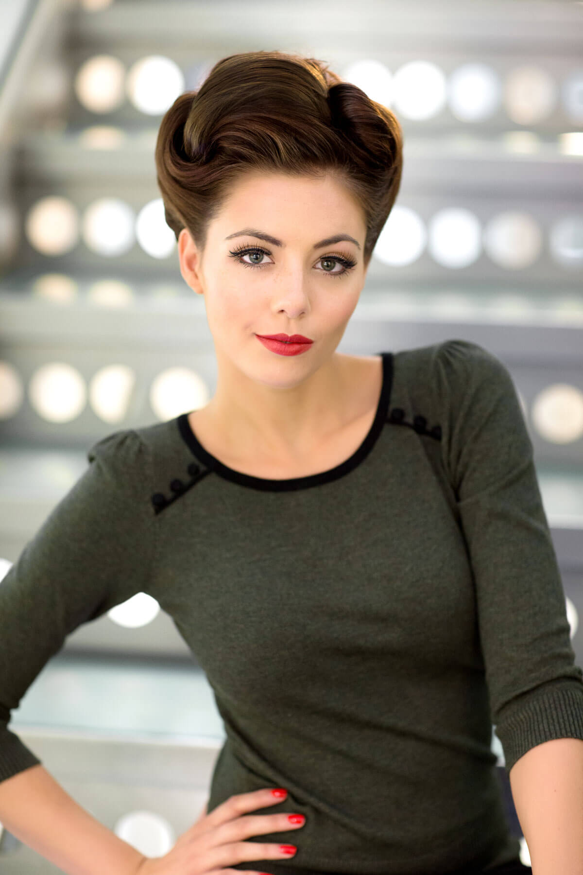 Woman with styled hair and red lipstick posing against a blurred indoor background. Beehive hairpiece hair height booster, Flexihair: Pixi chestnut brown 8