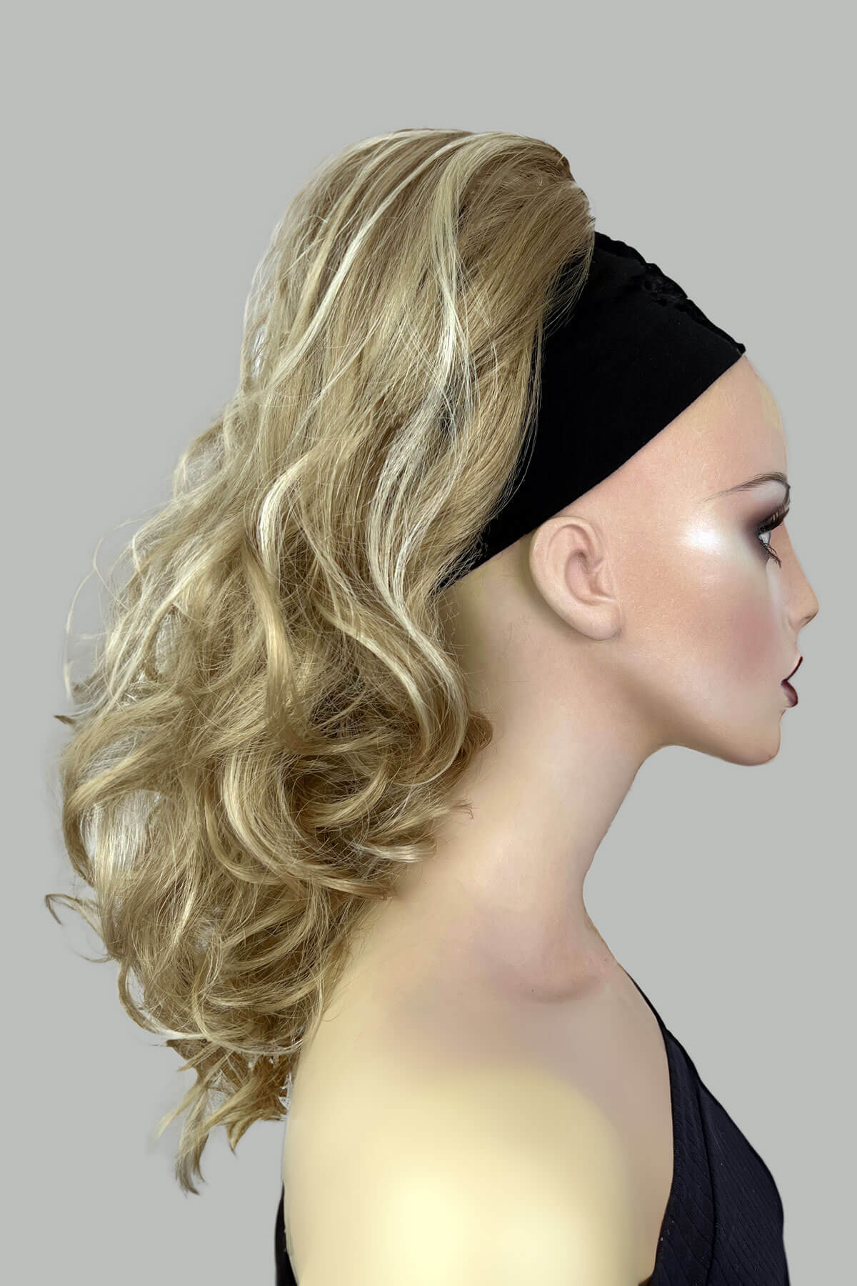 A woman wearing a floral off-shoulder top with a curly ponytail hairpiece extension in dark brown colour. blonde 24H613