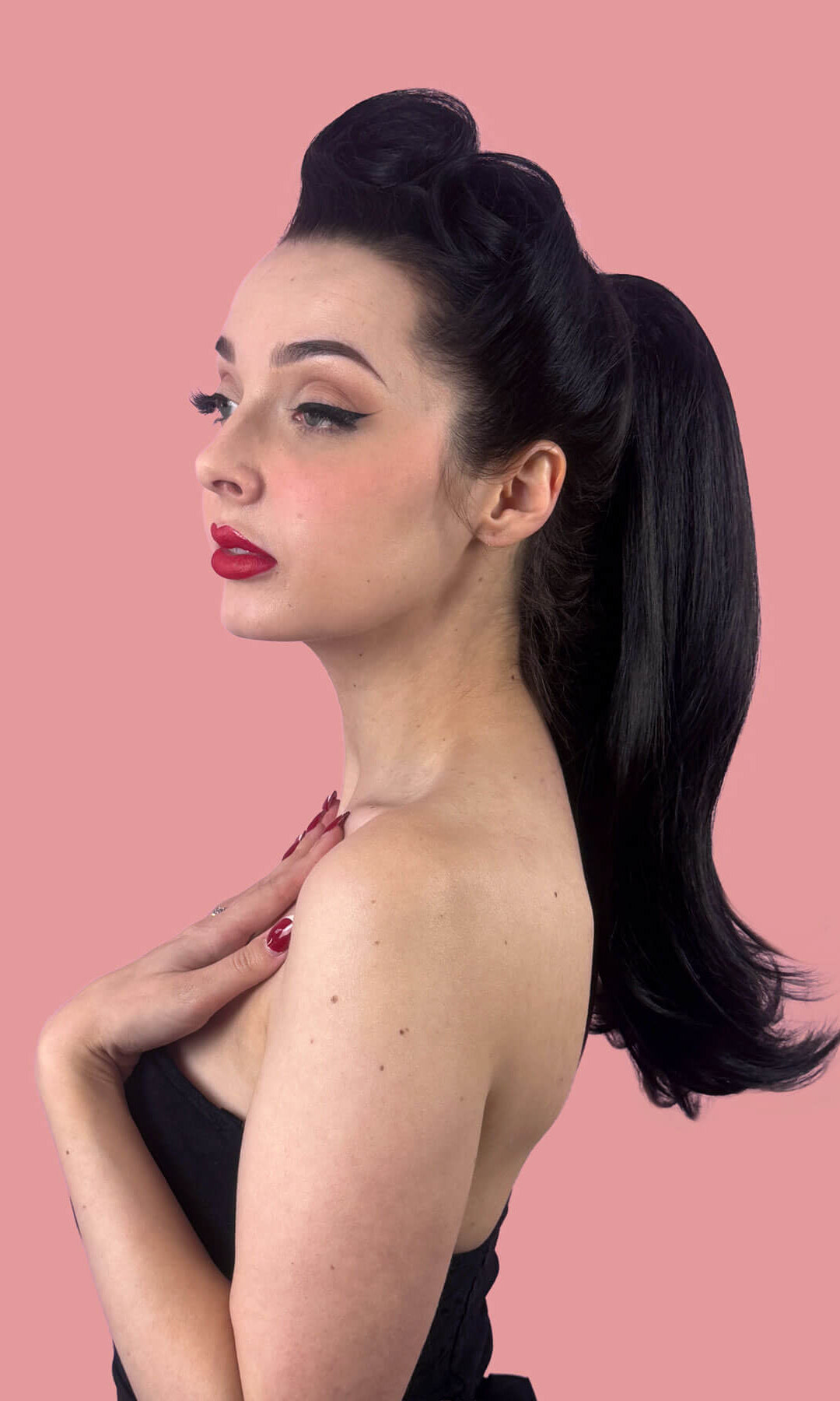 Woman with a long, black, high ponytail against a pink background. Long ponytail hairpiece, straight with flick: Clarisa black 1B