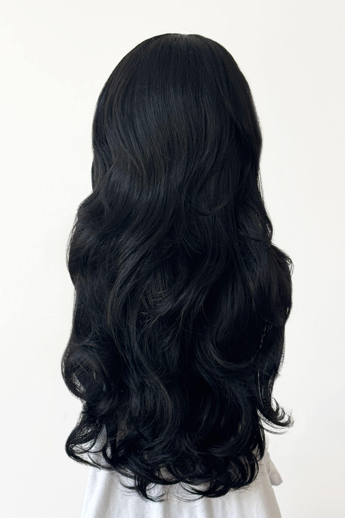Black wig on a mannequin head against a white background. Black curly half wig hairpiece (volume wig), big loose curls: Suzie