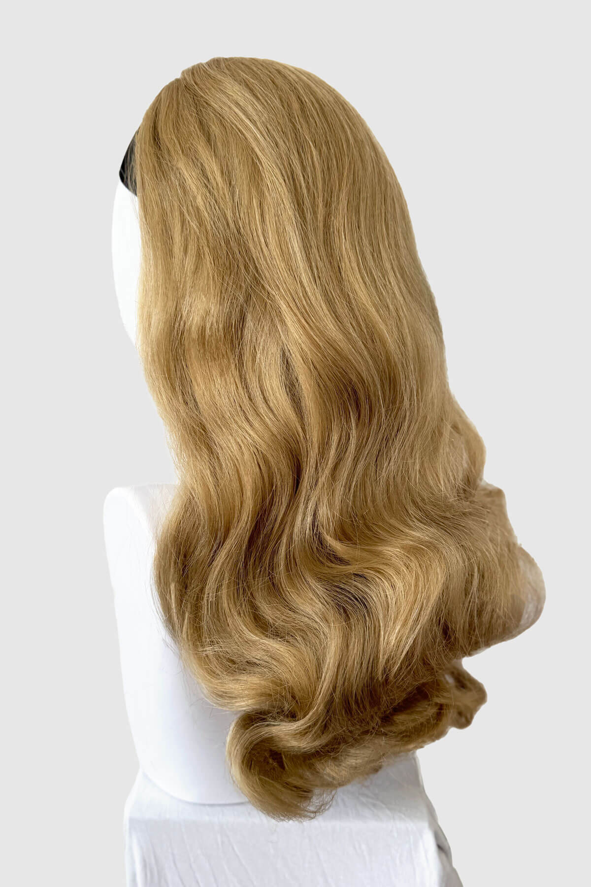 Blonde wig on a mannequin head against a white background. 1950s style half wig hairpiece with beautiful waves: Morgana blonde 24H613