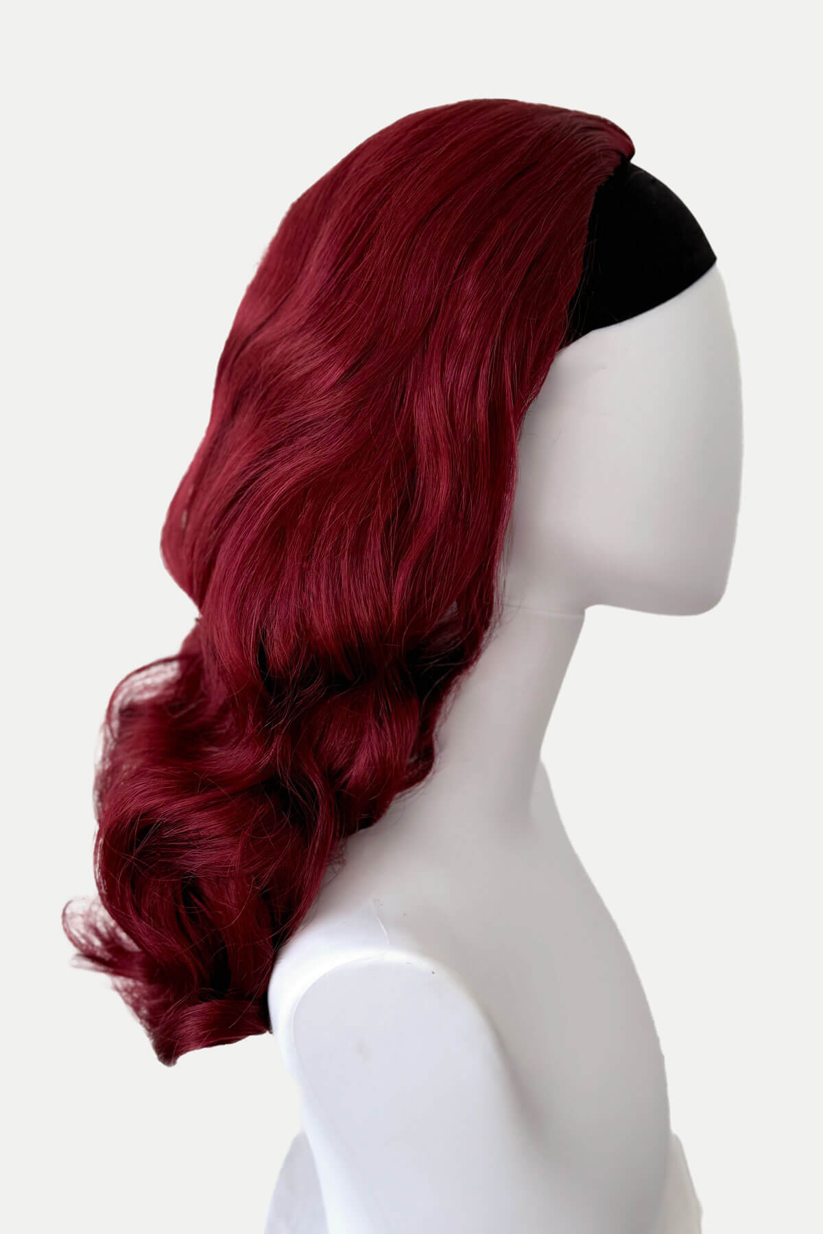 Red wig on a mannequin head against a white background. 1950s style half wig hairpiece with beautiful waves: Morgana red 39