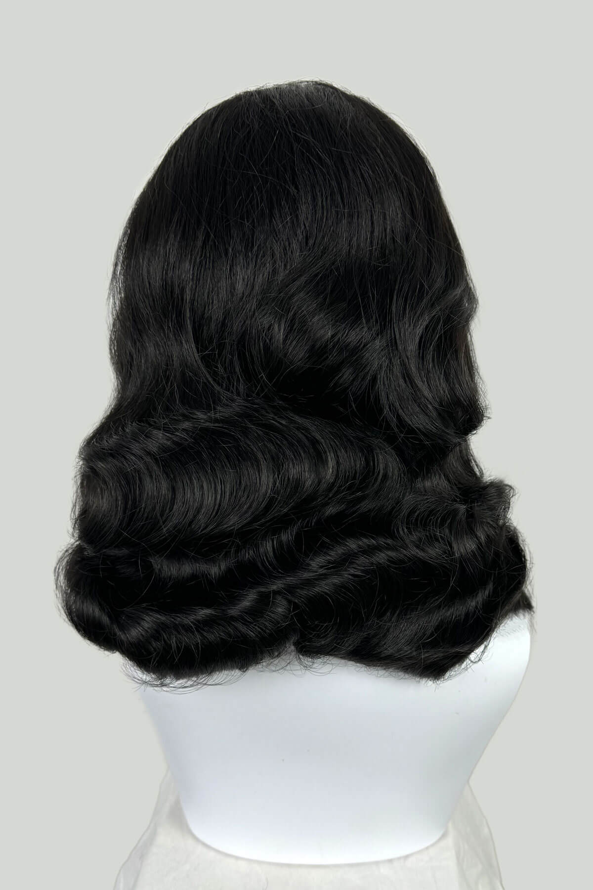 Black wig on a mannequin head against a white background. 1950s style half wig hairpiece with deep finger waves: Deborah black 1B