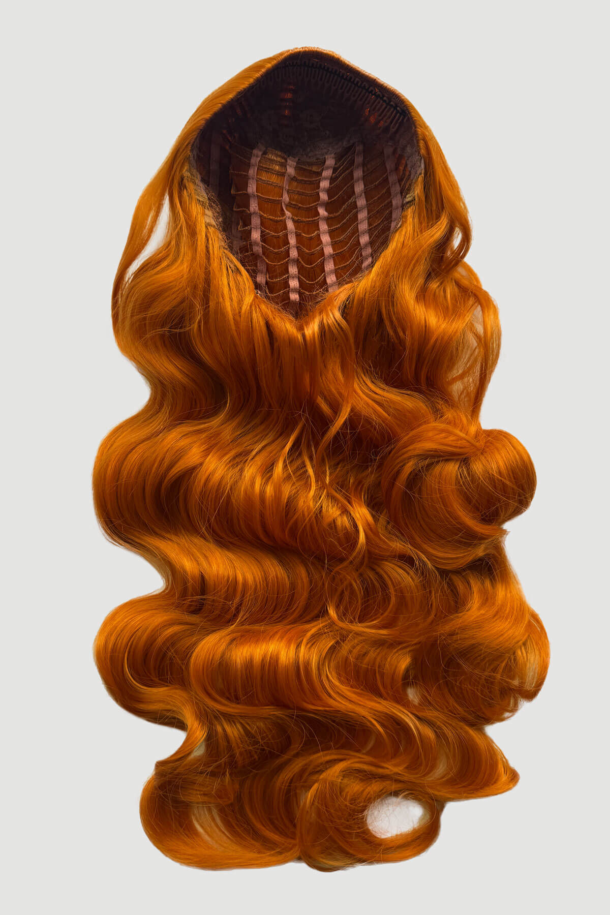 Mannequin head with long, ginger hair styled in a ponytail on a plain background. Ultra long half wig with hollywood waves. ginger