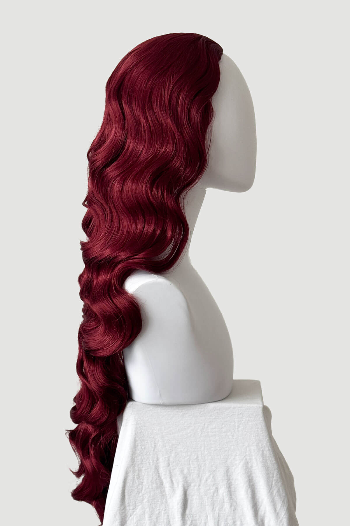 Mannequin head with long, red hair styled in a ponytail on a plain background. Ultra long half wig with hollywood waves. cherry red 39