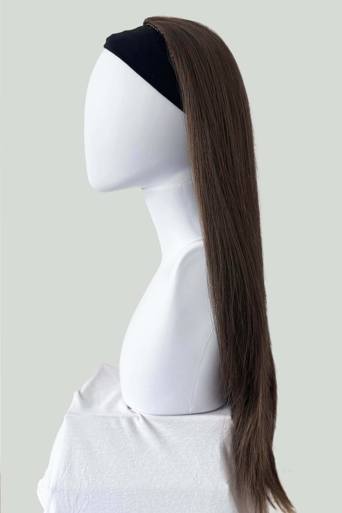 Brown hair extension on a mannequin head against a white background. Straight brown half wig hairpiece extension, long: Faye Mocha brown 10