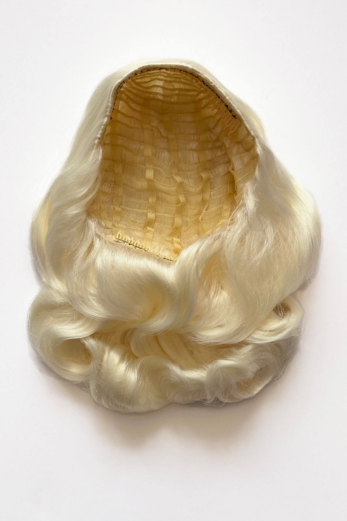 Blonde wig on a white background. 1950s style shoulder length half wig hairpiece with beautiful vintage waves: Onyx platinum blonde 1001