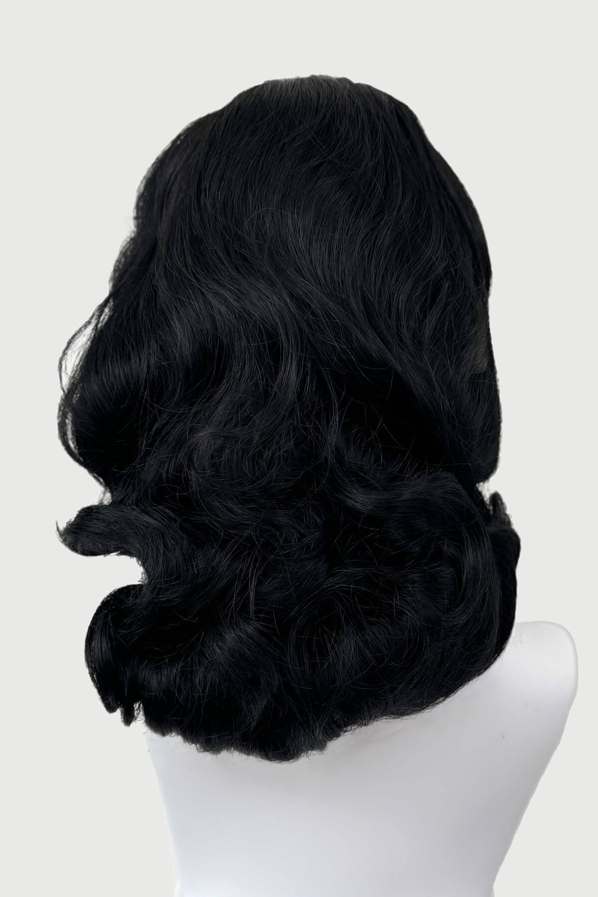Black wig on a mannequin head against a white background. 1950s style shoulder length half wig hairpiece with beautiful vintage waves: Onyx colour jet black 1