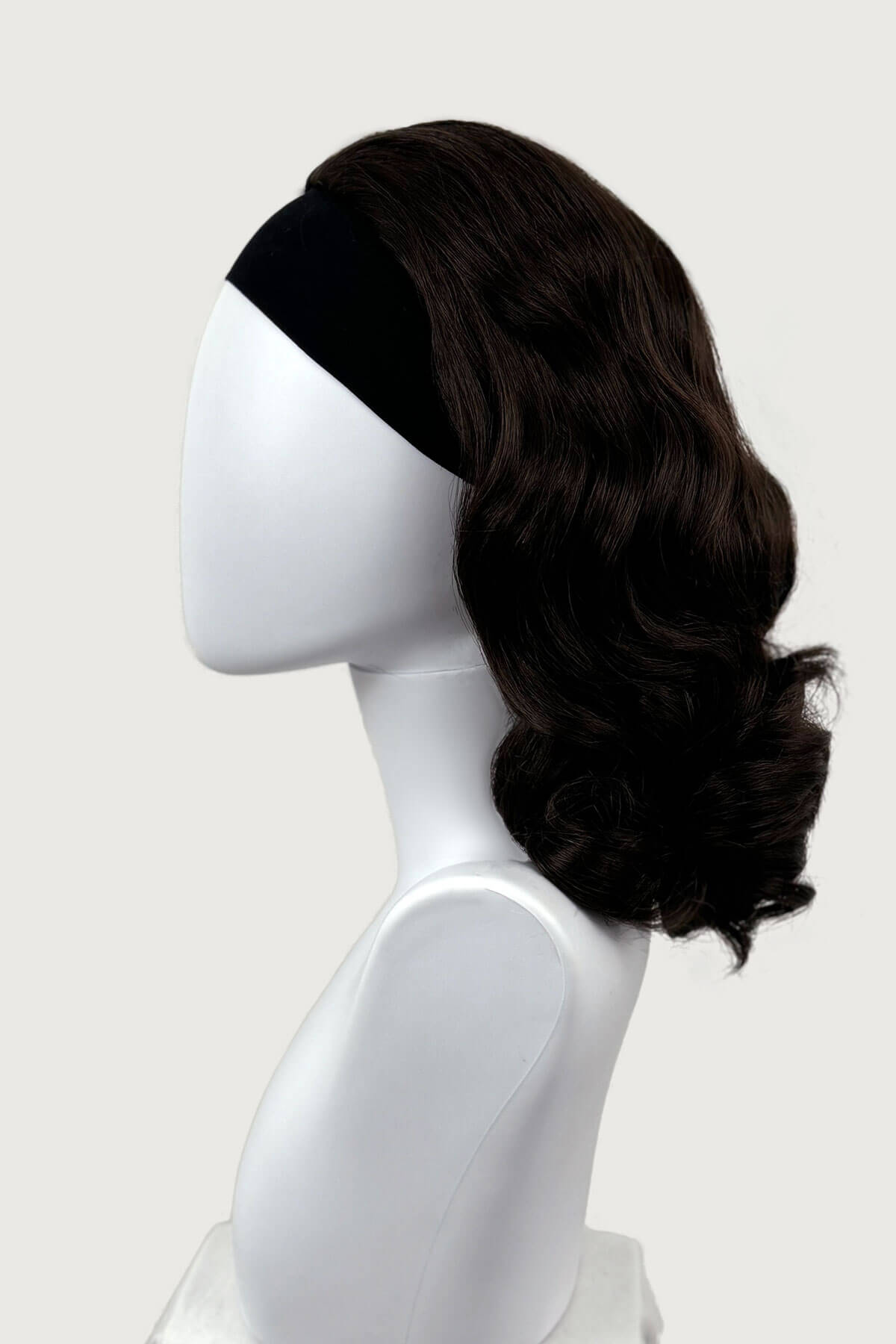 Dark chocolate brownwig on a mannequin head against a white background viewed from the side. 1950s style shoulder length half wig hairpiece with beautiful vintage waves: Onyx dark chocolate brown 6