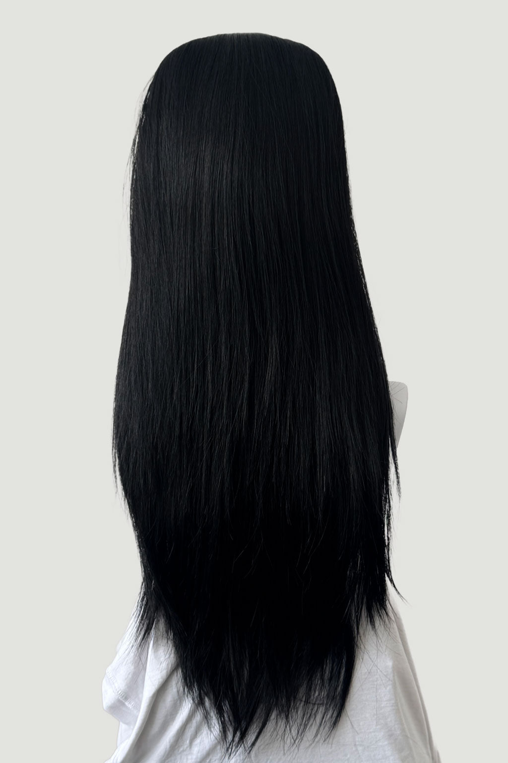 Black wig on a mannequin head against a plain background. 1960s style hair, high crown long straight half wig: Andrea black 1B
