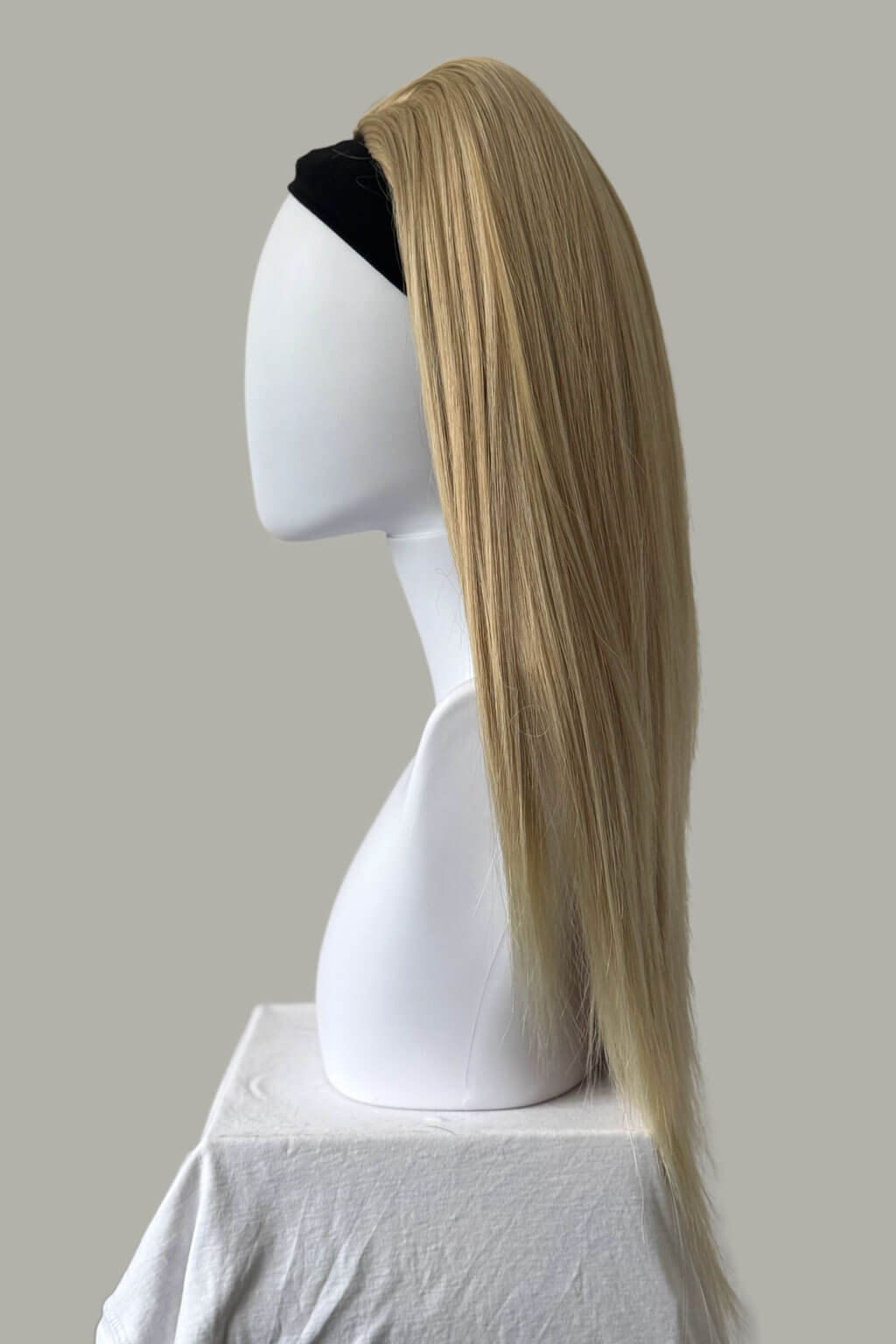 Blonde wig on a mannequin head against a plain background. 1960s style hair, high crown long straight half wig: Andrea blonde 613T24