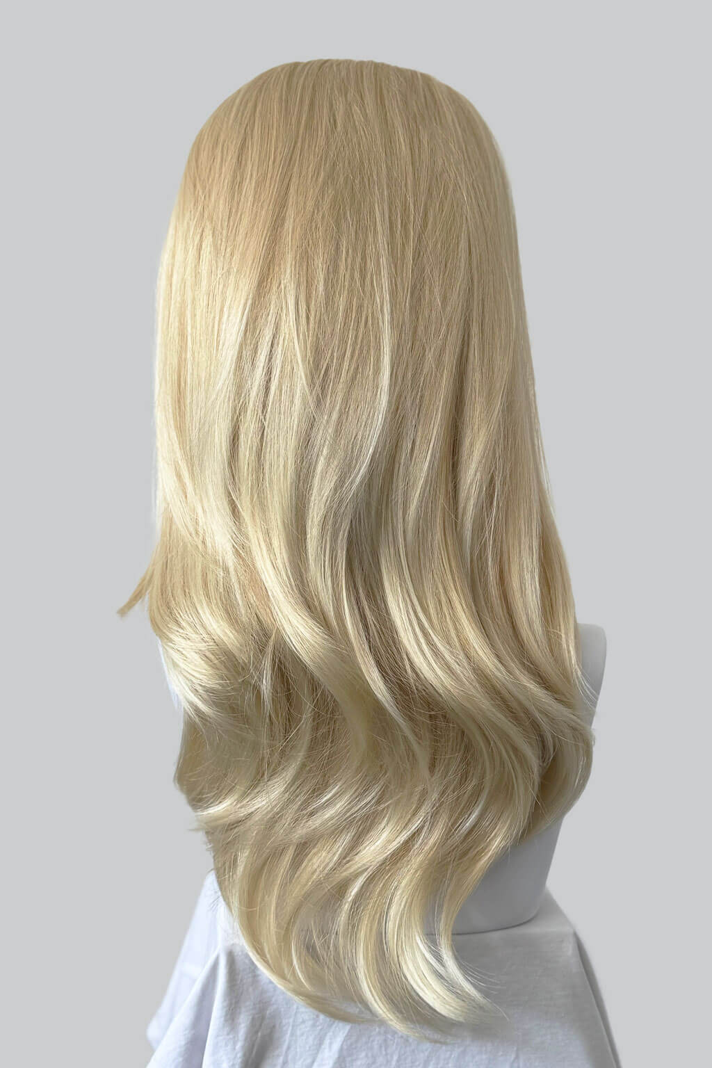 Blonde wig on a mannequin head against a plain background. 1960s style hair, high crown long straight and layered half wig: Juliette blonde 24BT613