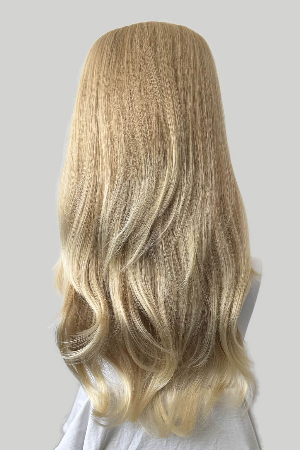 Blonde wig with wavy hair on a neutral background. 1960s style hair, high crown long straight and layered half wig: Juliette blonde 613T24