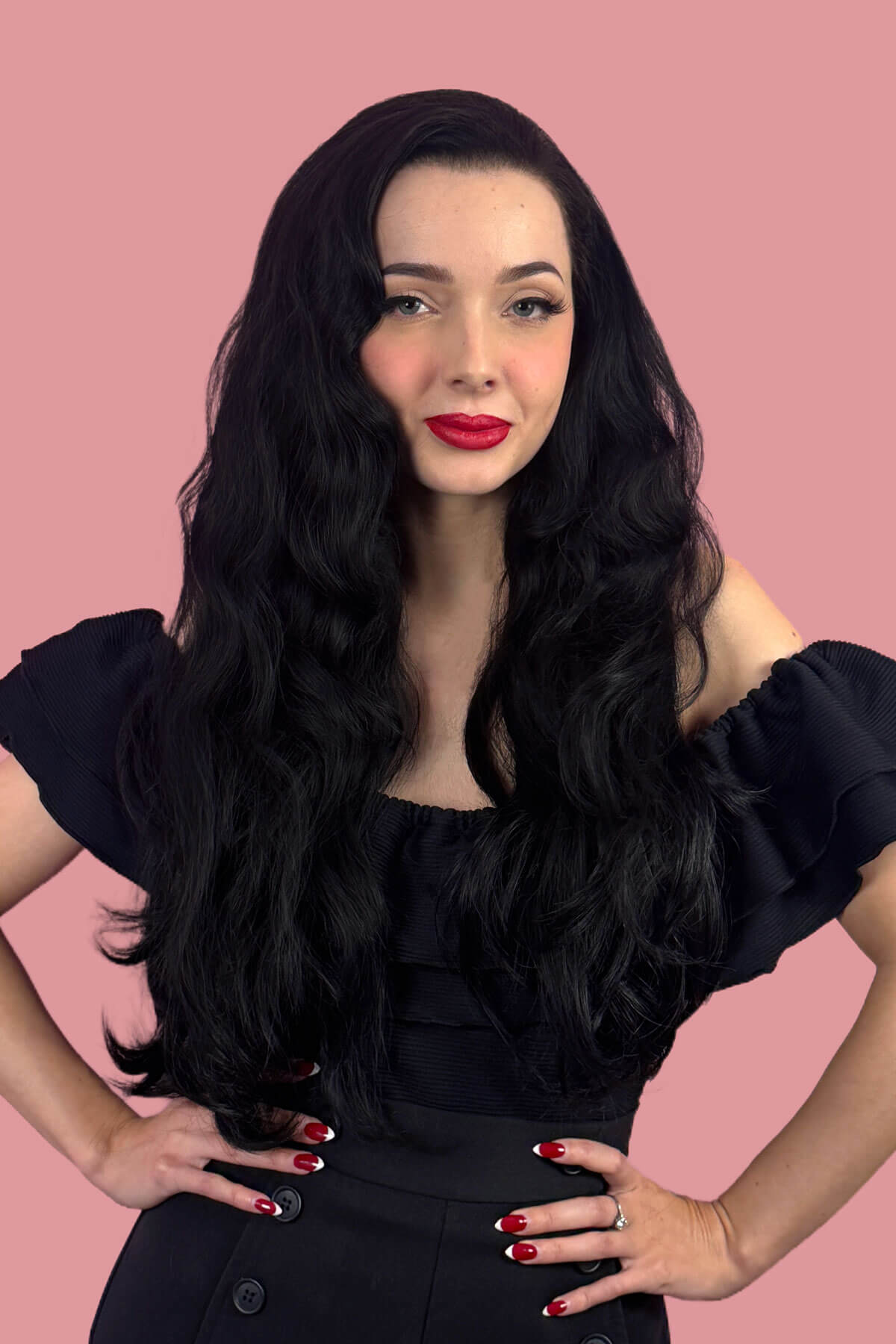 Woman with long black wavy hair and red lipstick posing against a pink background. Black half wig hairpiece (3/4 wig), long layers: Aislynn jet black 1