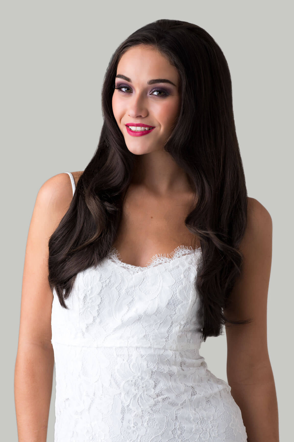 Woman wearing a white lace dress against a gray background
