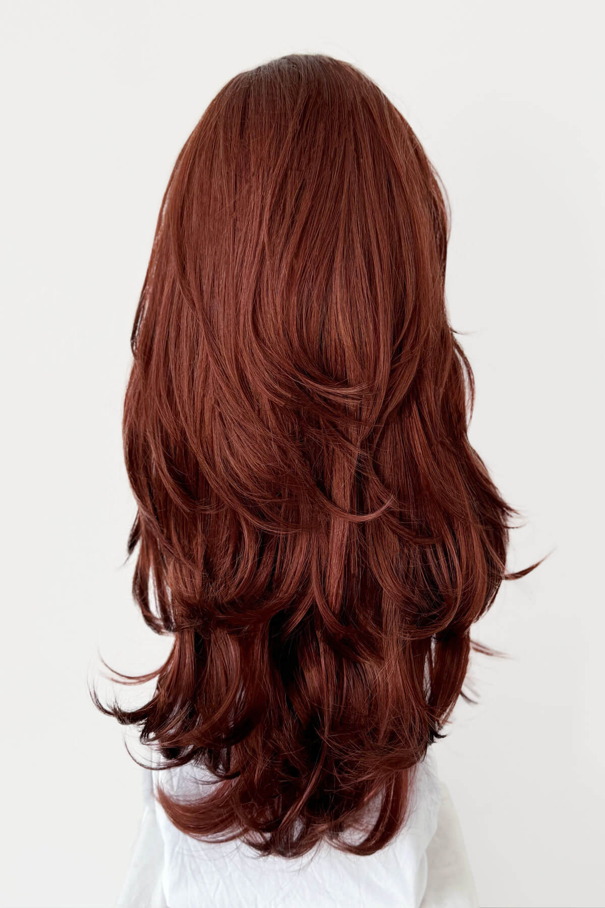 Long brown wig on a mannequin head against a white background. Red half wig hairpiece (3/4 wig), gentle curls: Ivy copper 130