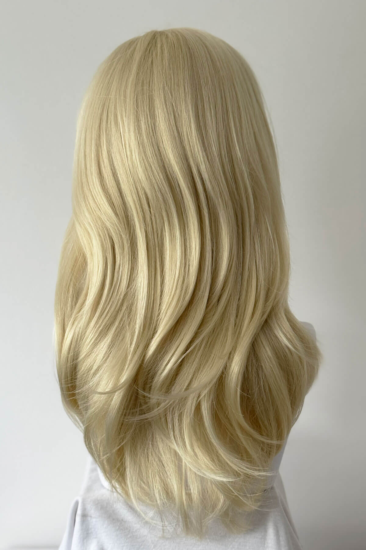 Blonde wig on a mannequin head against a plain background. Blonde half wig hairpiece (3/4 wig), gently layered: Sabrine champagne blonde 613