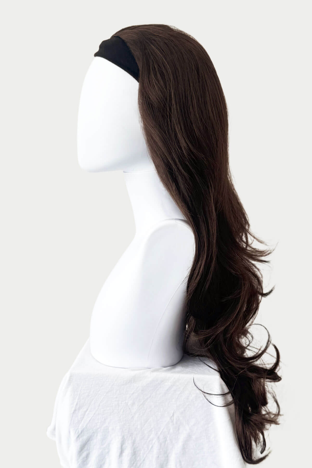 Mannequin head with long brown hair styled in a ponytail on a white background. Brown half wig hairpiece, full, long with gentle waves: Taya chestnut brown 8