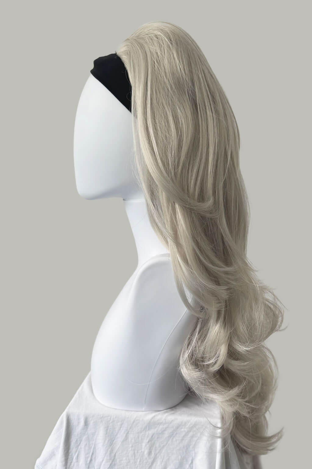 Blonde wig on a mannequin head against a plain background - High crown long, layered half wig and volume ring: Helena silver