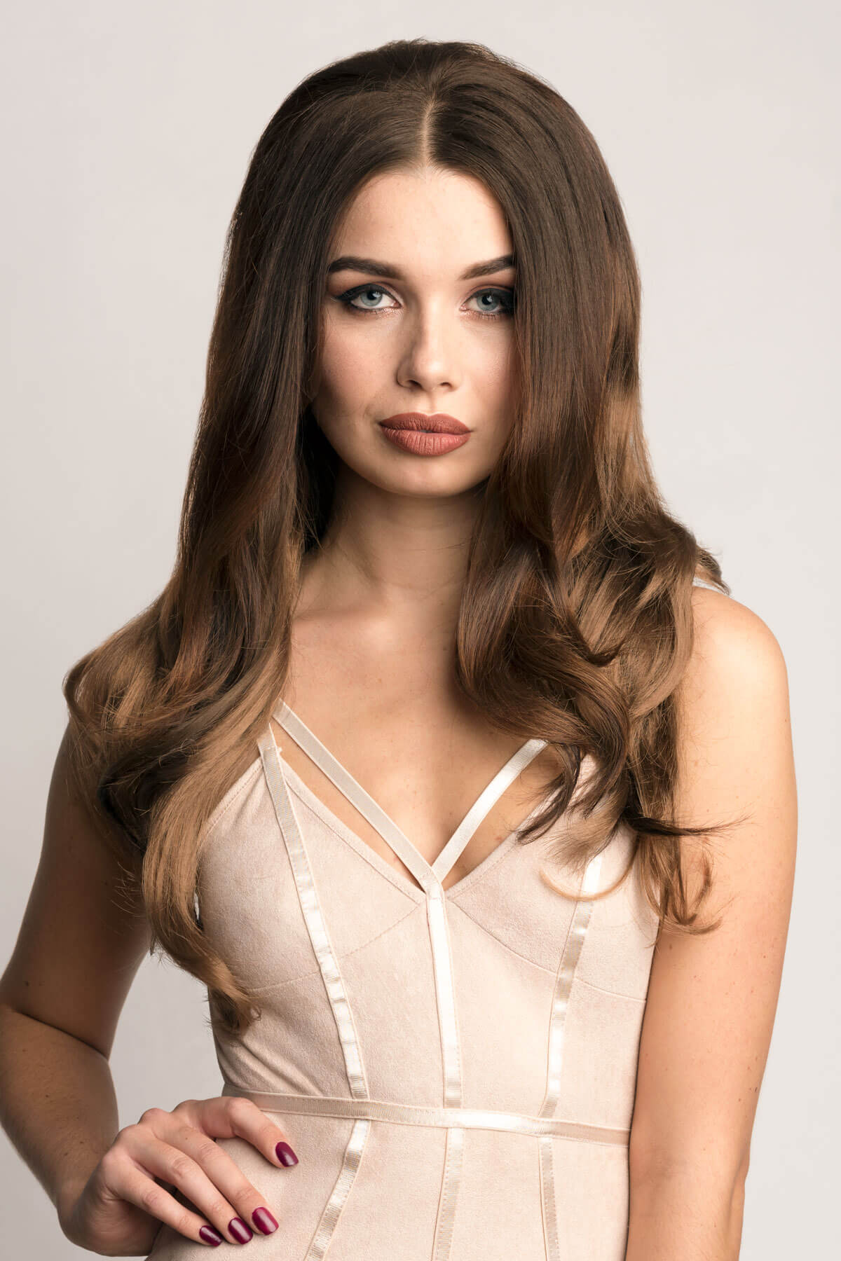 Woman with long, wavy hair wearing a beige dress against a plain background. Long brown half wig, dark brown blending to light brown: Lara