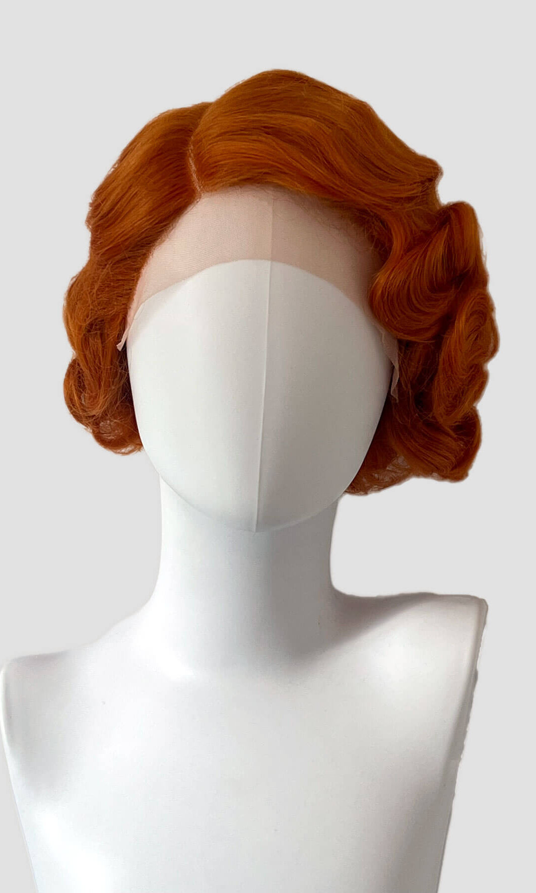 Red wig on a mannequin head against a white background. Ginger pinup wig, lace front, vintage style: Flo