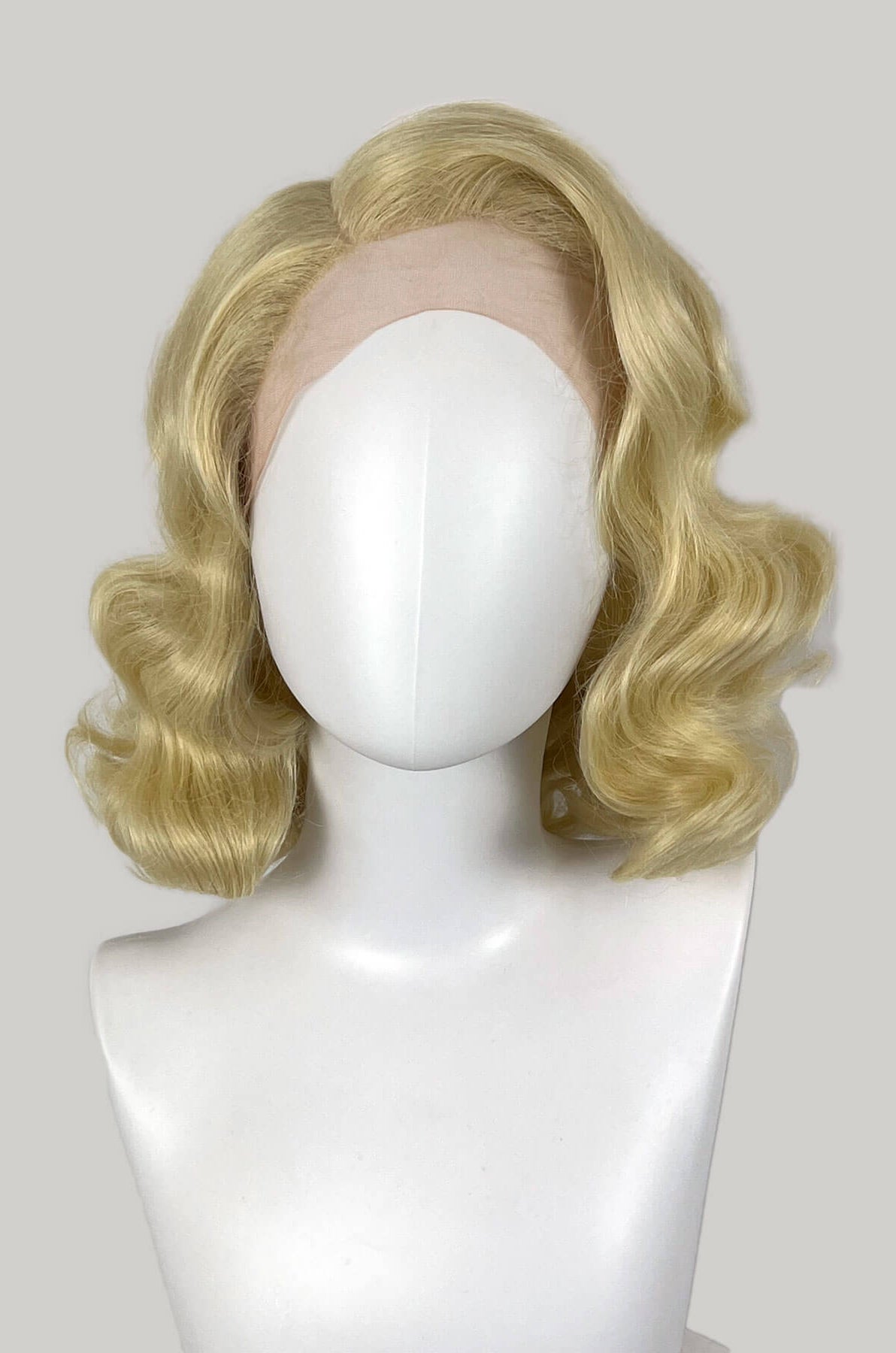 Blonde wig on a mannequin head against a white background. Blonde lace front wig, pinup/vintage style, mid length with finger waves: Lucinda