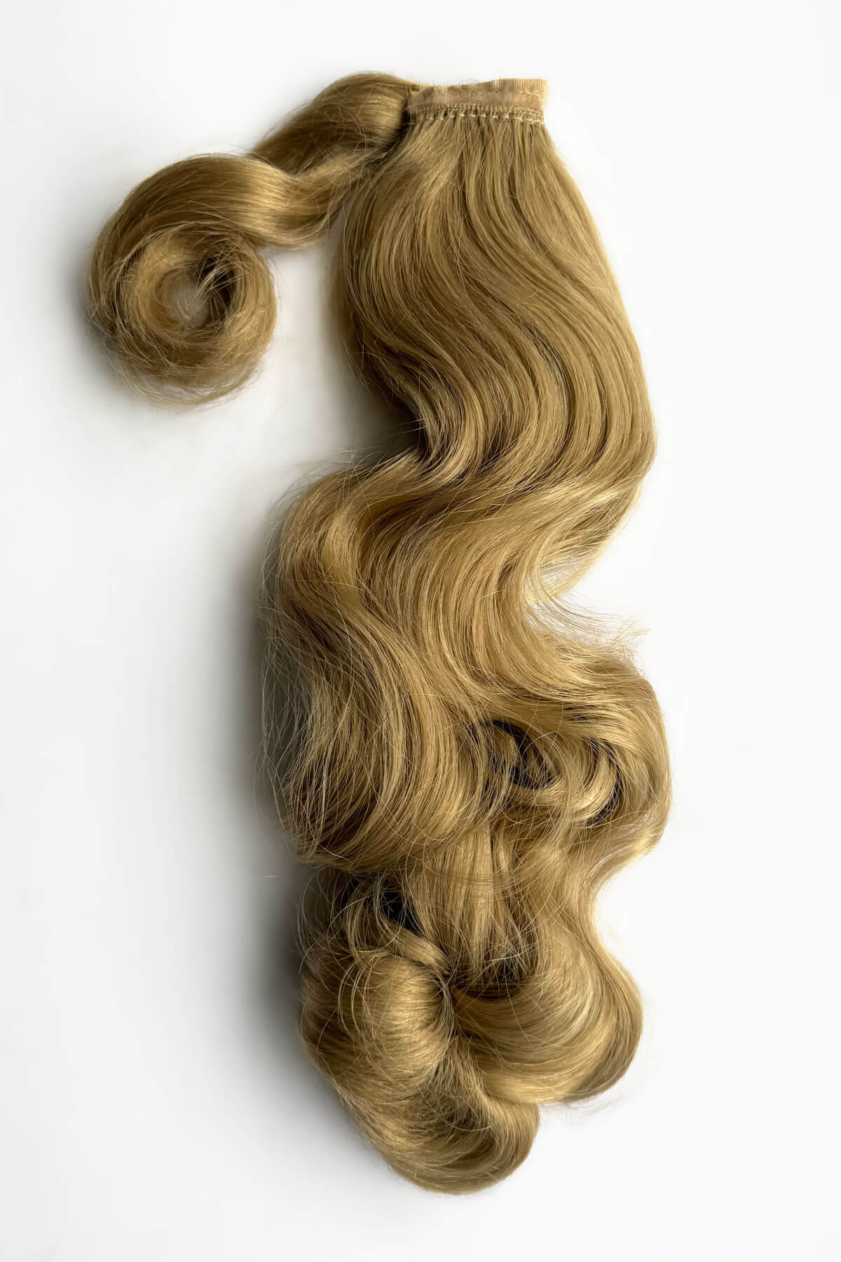 Blonde hair extensions styled in loose waves on a white background. Retro style ponytail hairpiece, long with vintage waves: Arabella