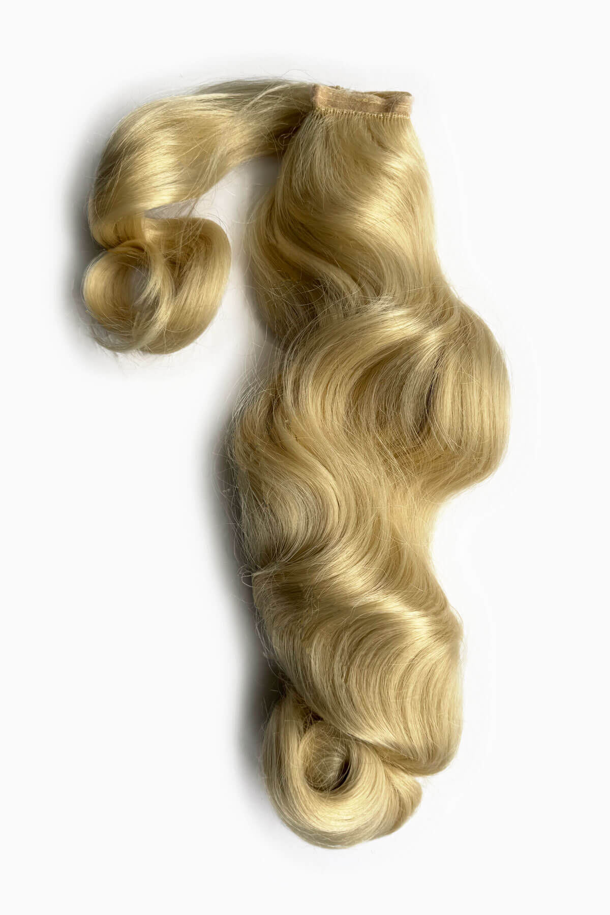 Blonde hair extension with wavy texture on a white background. Retro style ponytail hairpiece, long with vintage waves: Arabella champagne blonde 613