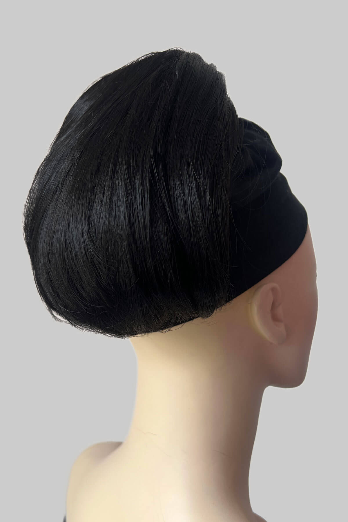 A mannequin wearing a green top and a beehive ponytail hairpiece in a soft blonde color. Short beehive ponytail hairpiece: Sherri Black 1B