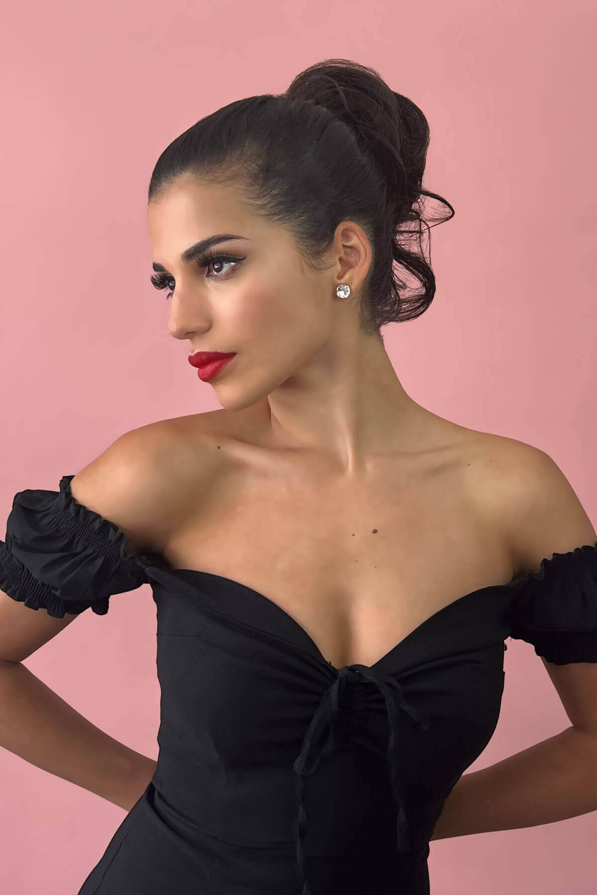 Woman in a black off-shoulder dress with red lipstick against a pink background. Short ponytail extension hairpiece, short with whisps: Leah brown and blonde 4TN27