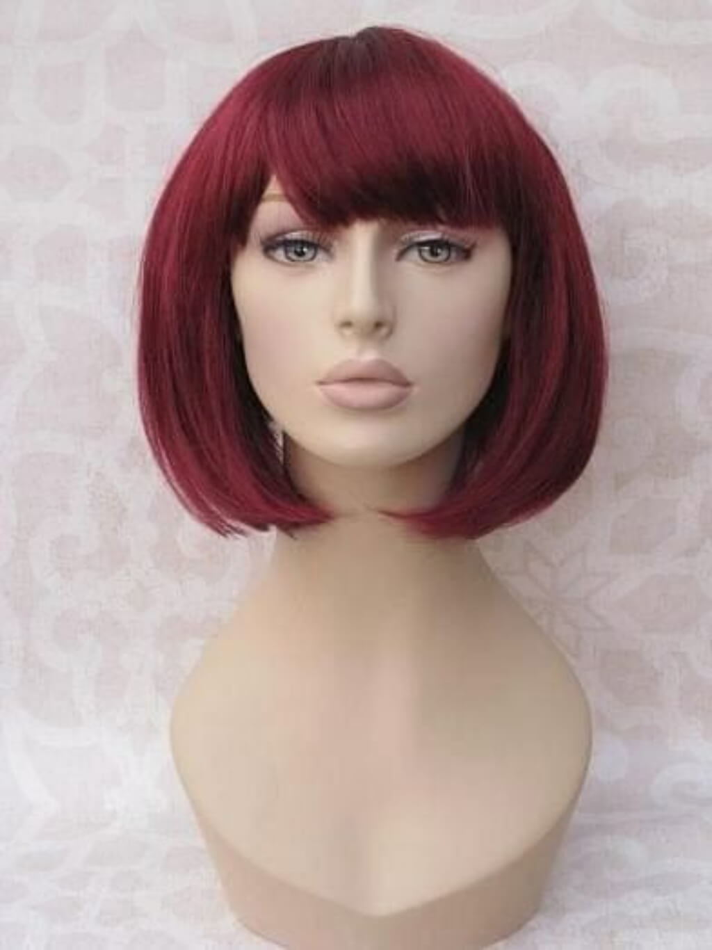 Red wig on a mannequin head against a light background. Red inverted bob wig, short and chic: Flavia