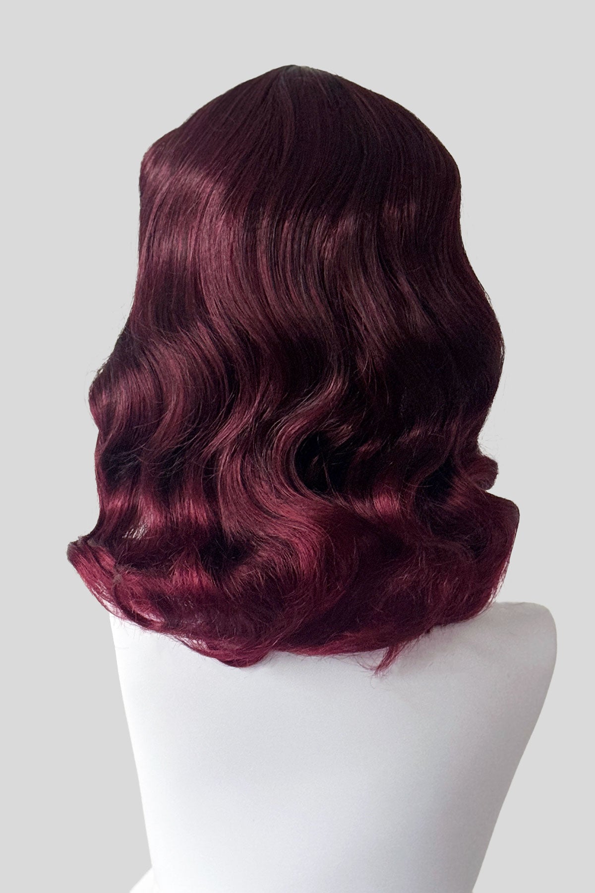 Mannequin head with a black and red wig on a white background. Black and red pin-up style wig, gently wavy with short fringe: Lillian