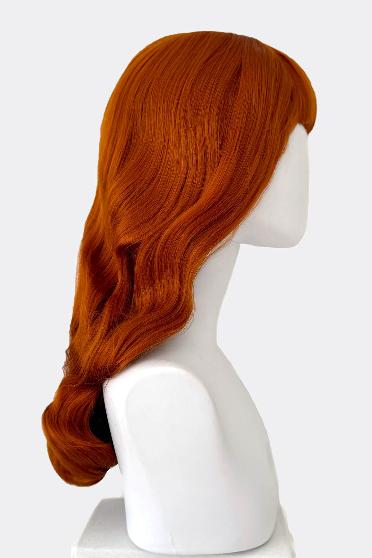 Red wig on a white mannequin head against a white background. Ginger wig, pinup style with short fringe and gentle waves, 1950s style: Vida