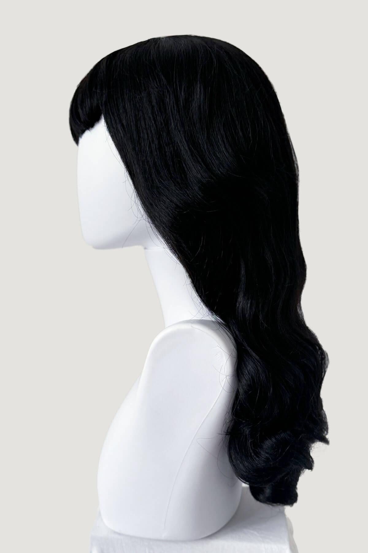 Black wig on a white mannequin head against a light gray background. Long black 1950s pin up style wig with platinum streak and retro fringe: Michelle