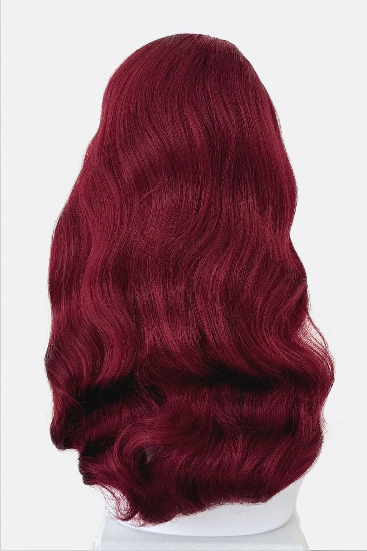 Red wig on a mannequin head, from behind, against a white background. Long cherry red pin-up wig, gently wavy with short fringe: Maeve
