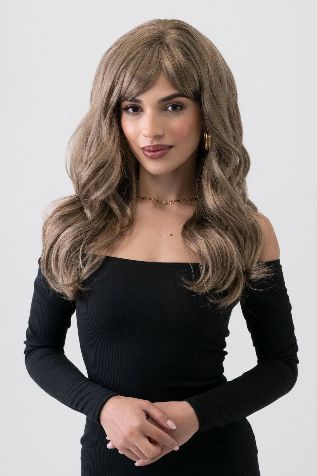 Woman wearing a long brown wig against a white background. Light brown wavy wig with ash blonde highlights: Cata