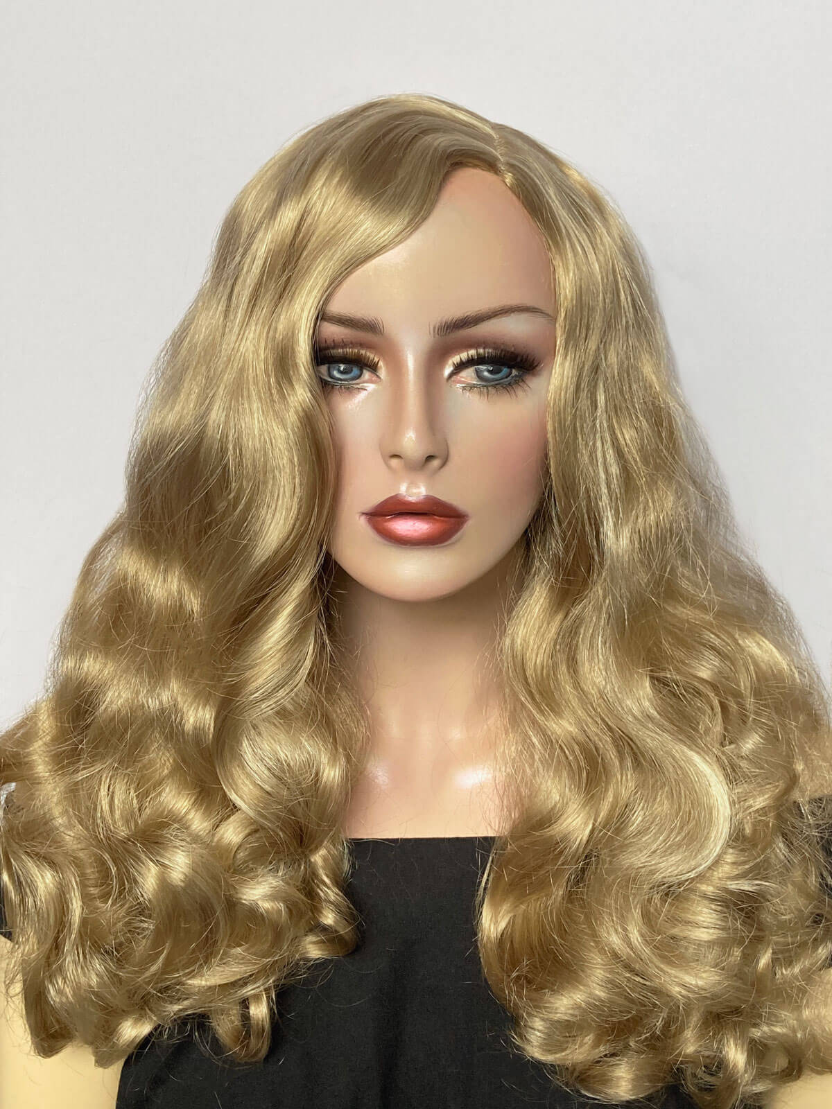 Mannequin head with long blonde wavy hair on a plain background