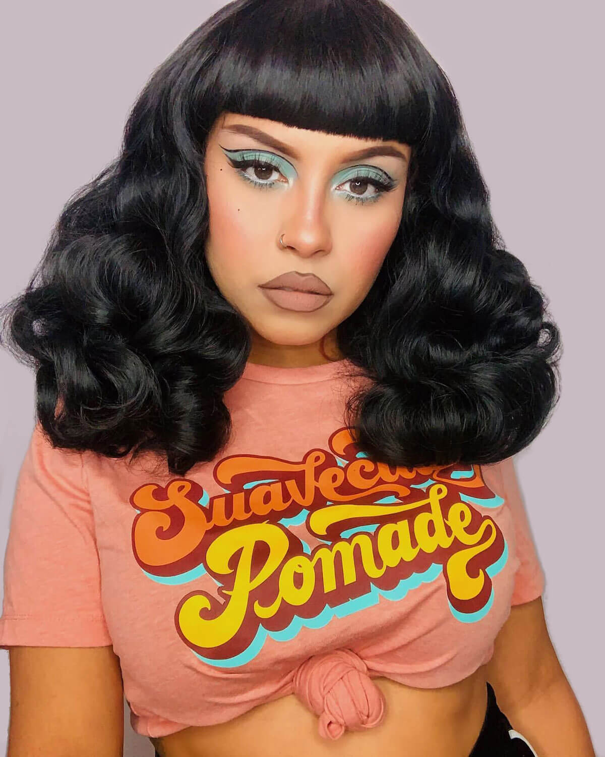 Person wearing a pink t-shirt with 'Suavecito Pomade' text against a plain background