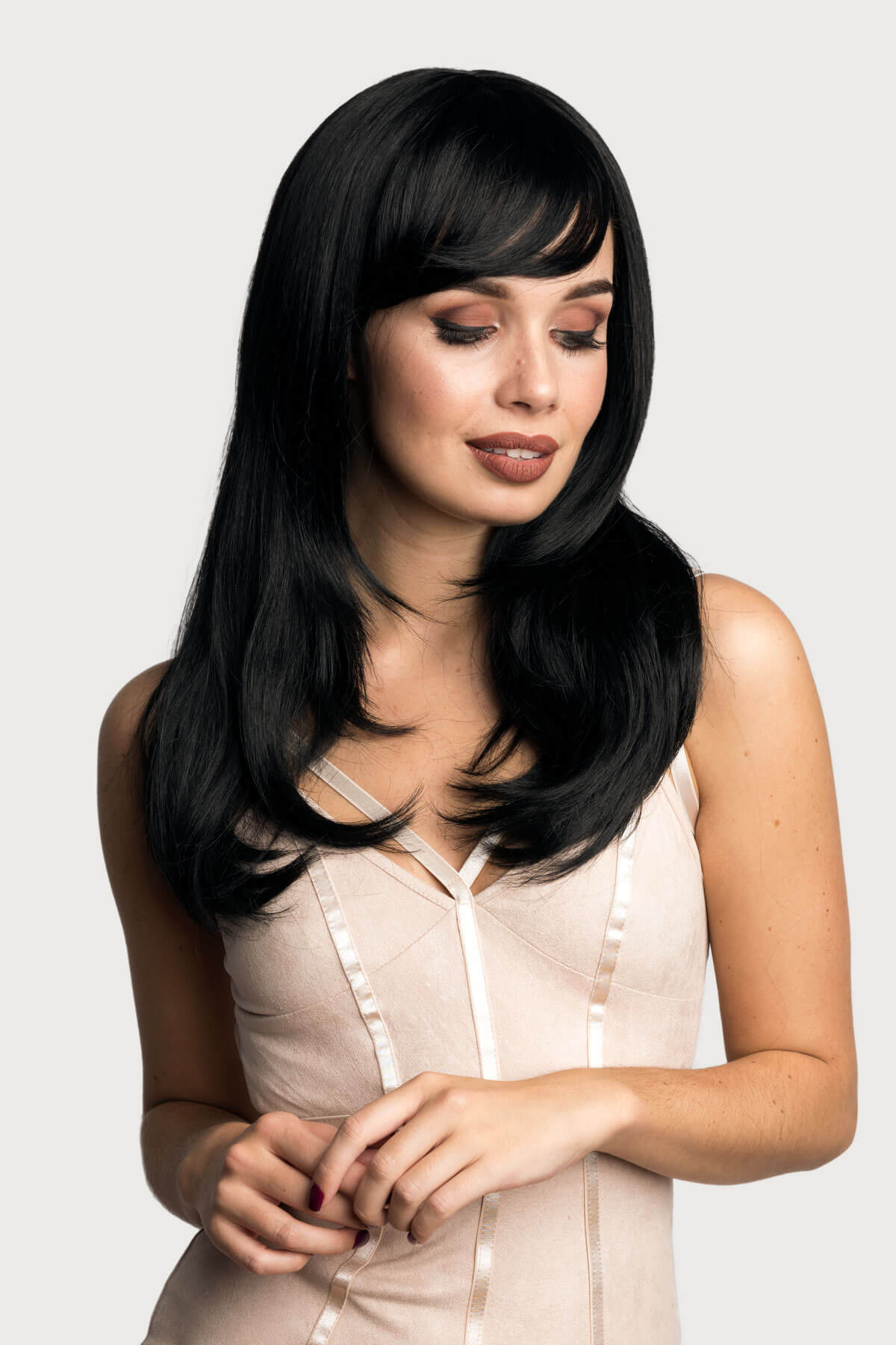 Woman with long black hair wearing a beige top on a white background. Long black wig, face frame style with full, sweeping fringe: Corina
