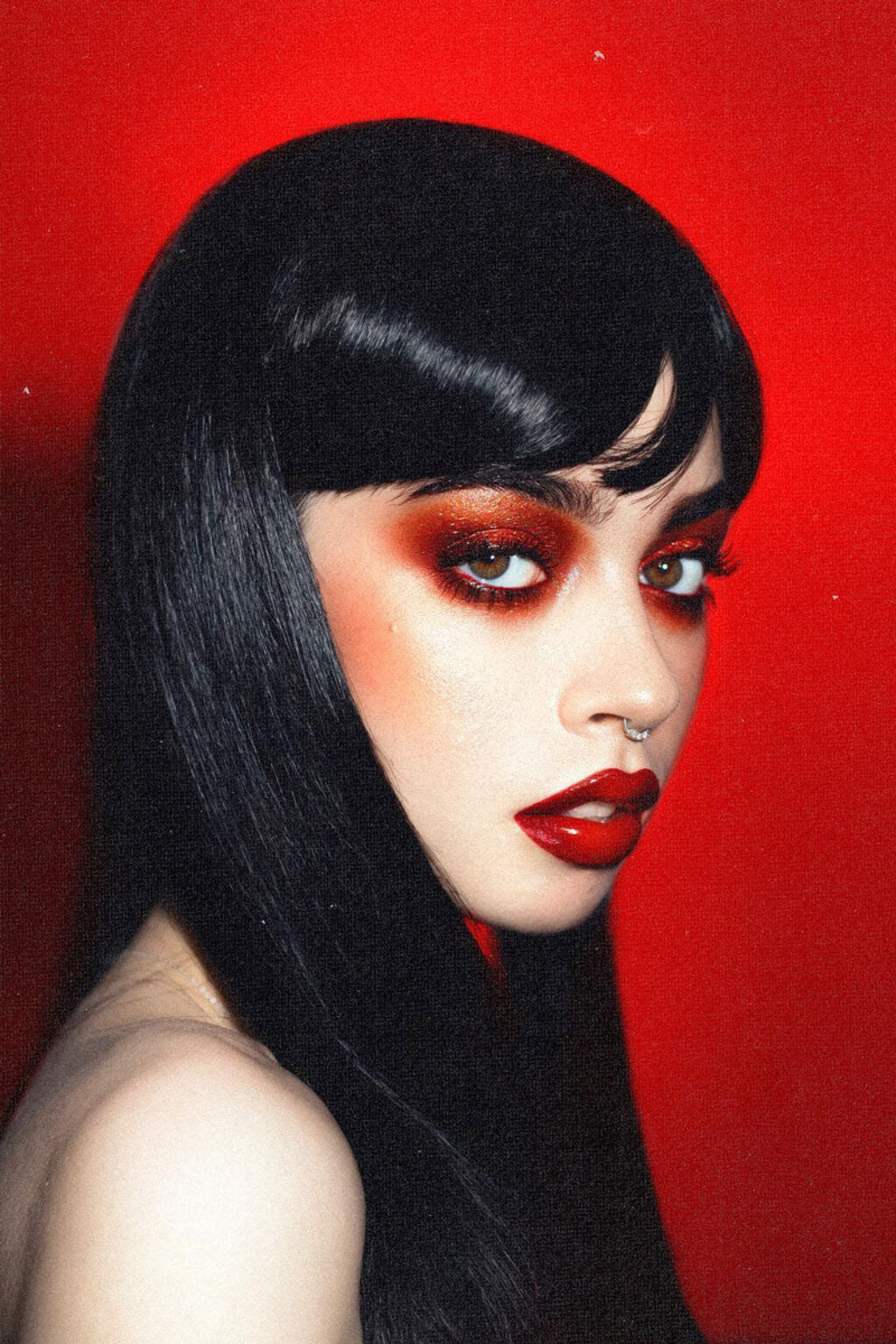 Woman with black hair and red makeup against a red background. Long straight black wig with straight fringe: Carmen