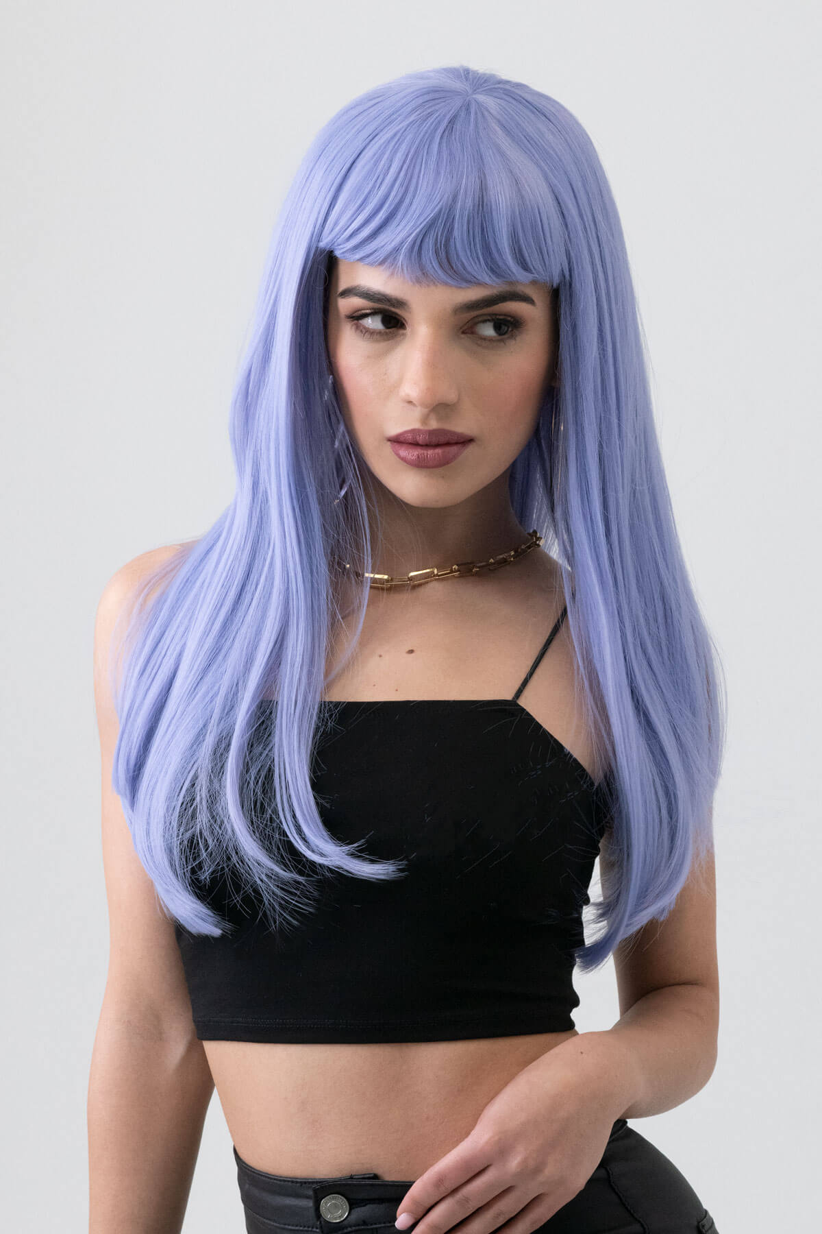 Woman with long purple wig wearing a black top on a white background. Long blue wig with short, straight fringe: Alyssa